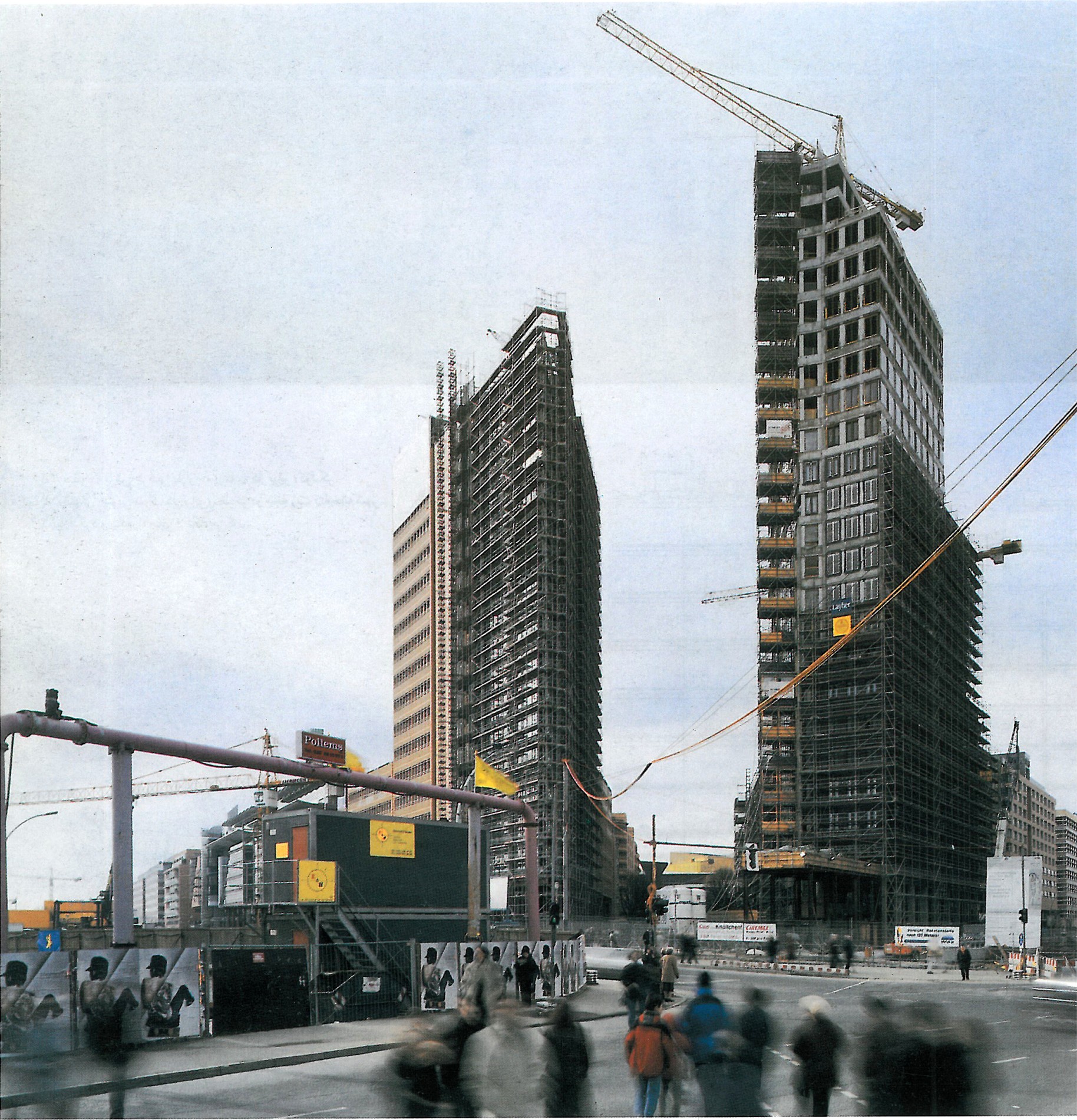 Construction-stage view of the Piano–Kohlbecker towers with cranes and scaffolding above the plaza