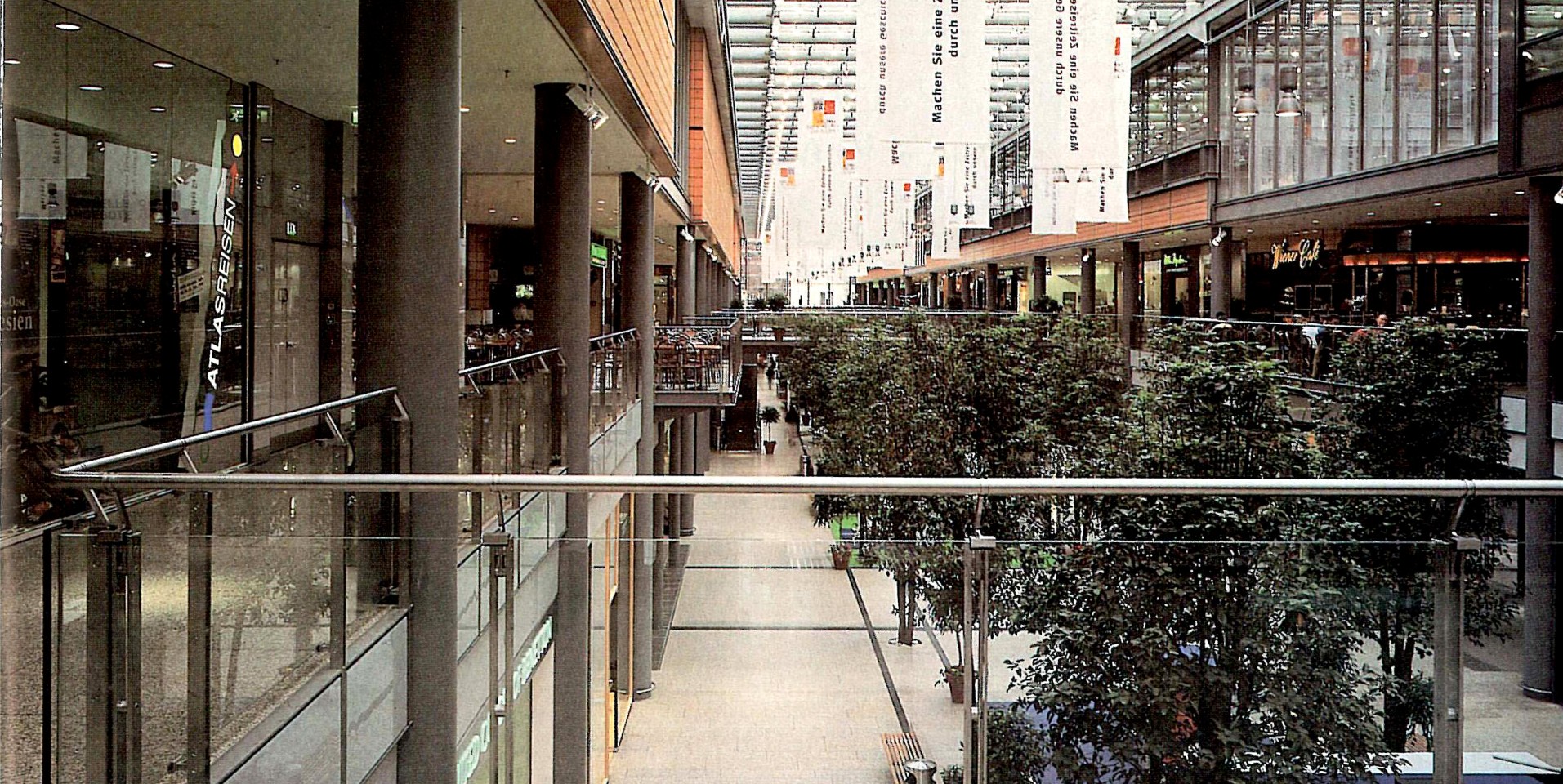 Interior of the Arkaden shopping street, with its glass roof and hanging planting