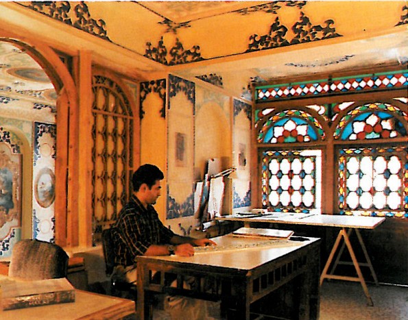 Interior of a high-ceilinged Esfahani reception room after restoration, with two large stained-glass orosi windows letting coloured light onto plastered walls and rugs.
