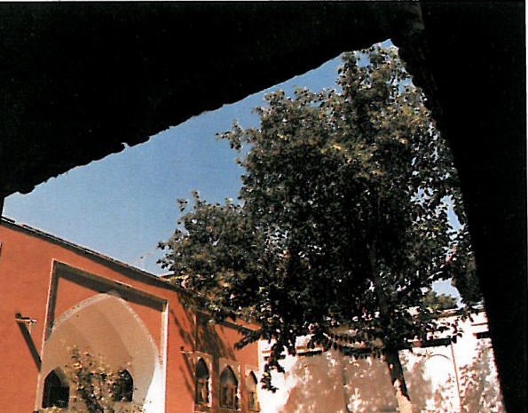 Detail photograph of a restored stained-glass arched window with rich geometric tracery, set below a stuccoed ceiling.