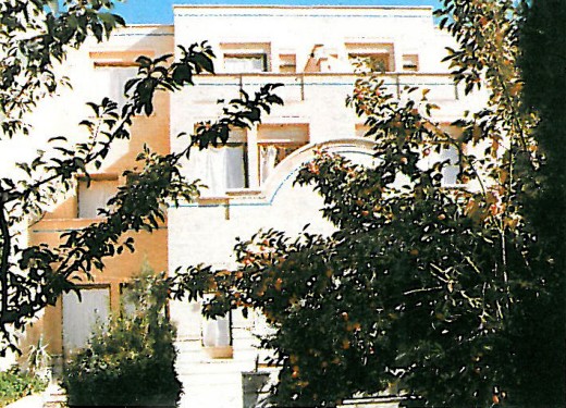 Photograph of the House of Roghani: a brick masonry residence with deep-set windows partly screened by foliage, in the polsheer firm's late-1990s residential vocabulary
