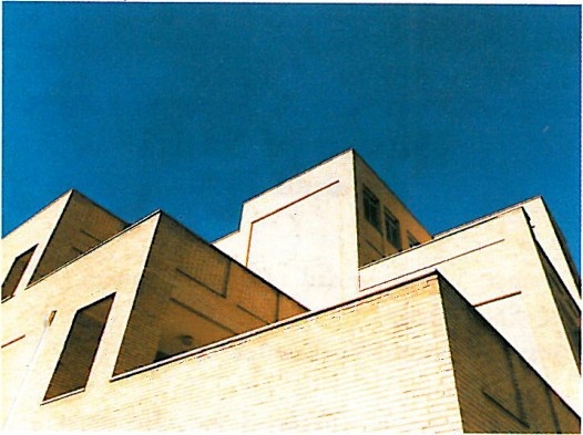 Cluster of zinc-clad asymmetric gable roofs forming a residential complex, photographed against a deep blue sky.