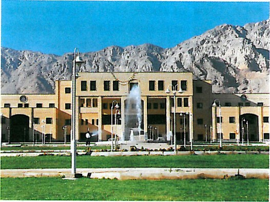Long symmetric brick administration building of Isfahan University of Technology, photographed across a reflecting pool with arid mountains behind.