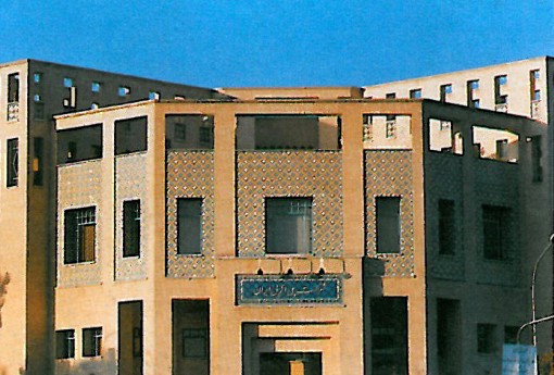 Three-storey buff-brick office building with recessed window bays and a stepped silhouette, on the grounds of the Polyacryl petrochemical plant.