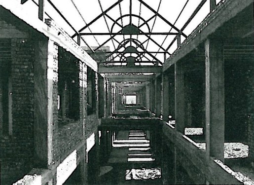 Interior of the Koat Banoon centre — a vaulted corridor with metal mesh ceiling, mosaic floor and warm artificial light at the far end