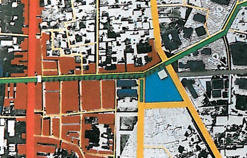 Coloured urban master plan in plan view: existing buildings rendered in warm earth tones, new public open spaces highlighted in blue and yellow.