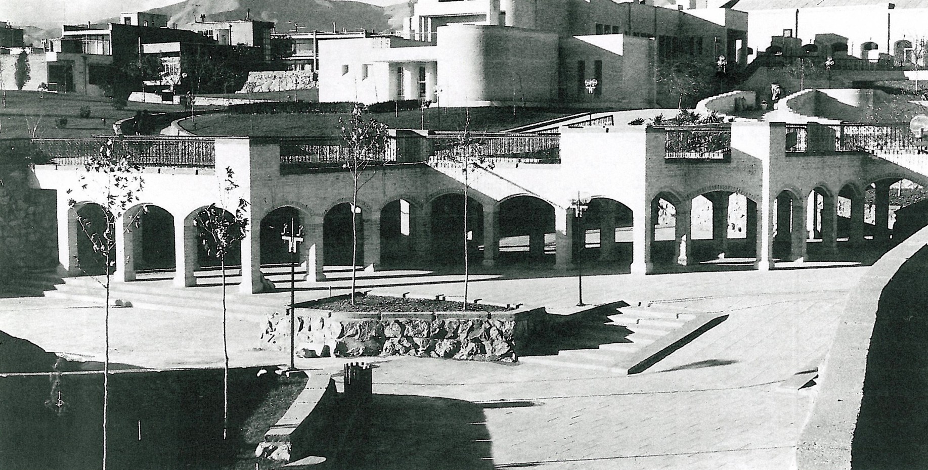 Wide-angle photograph of Park Shafagh in Tehran with arcaded brick pavilions, central plaza and mountain backdrop