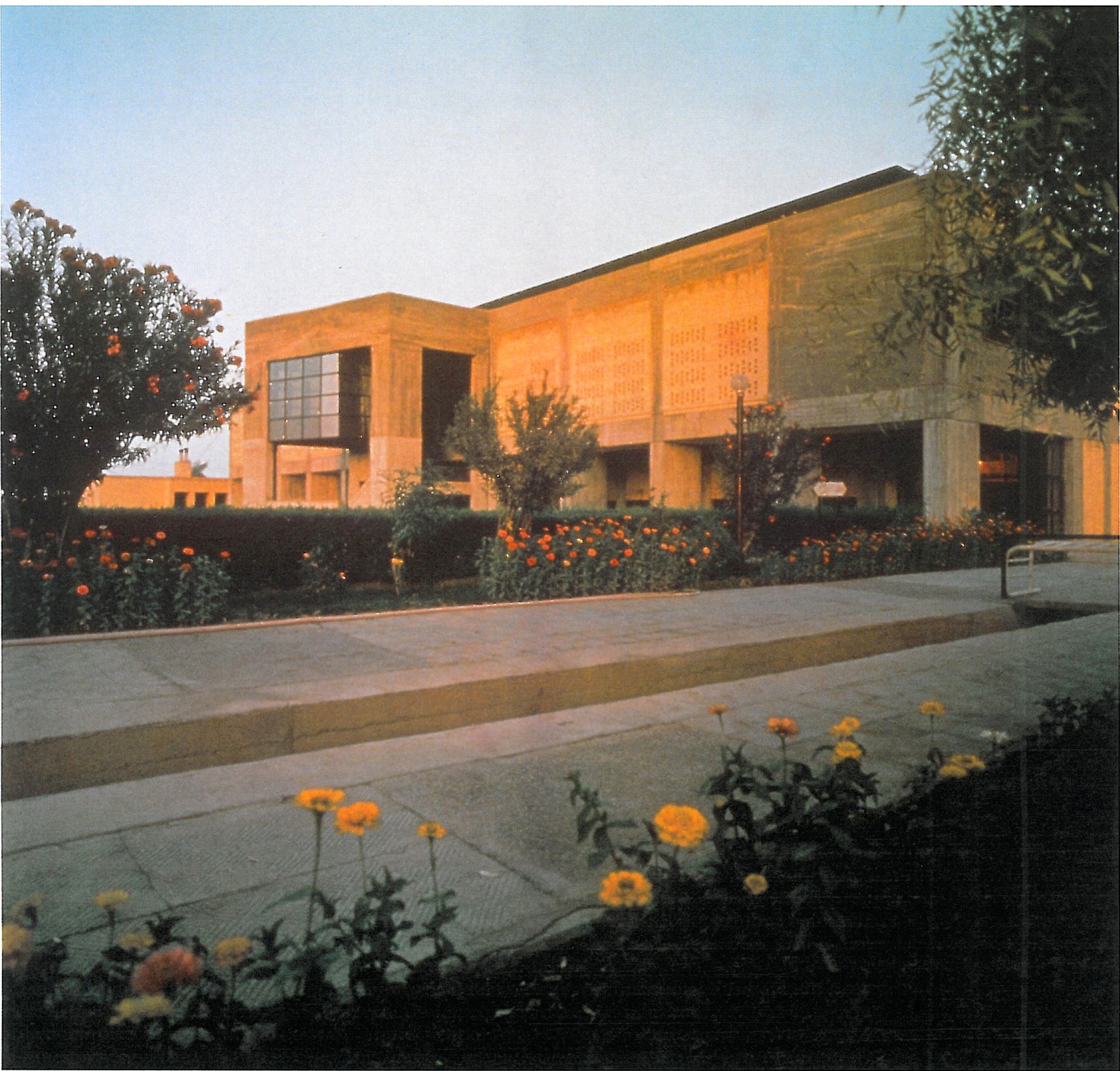 Jondi-shapur University Gymnasium at twilight, looking through the open colonnade toward a marigold garden