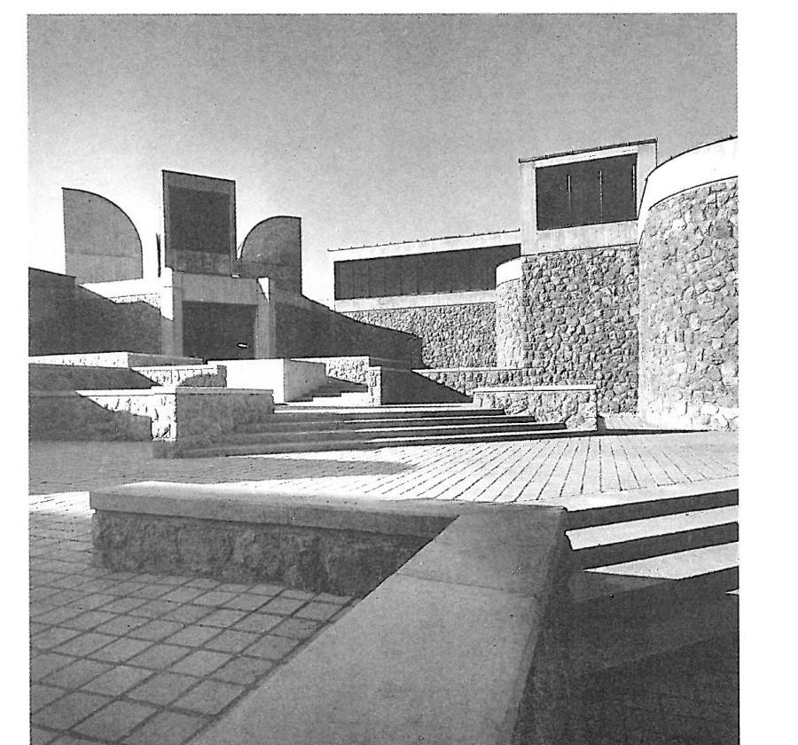 Exterior photograph of the Tehran Museum of Contemporary Art seen from the sunken sculpture plaza, with a row of curved metal skylight vaults punctuating the masonry roofline