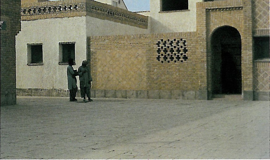 First-Phase neighborhood at Shushtar New Town with two figures conversing in a brick-paved alley