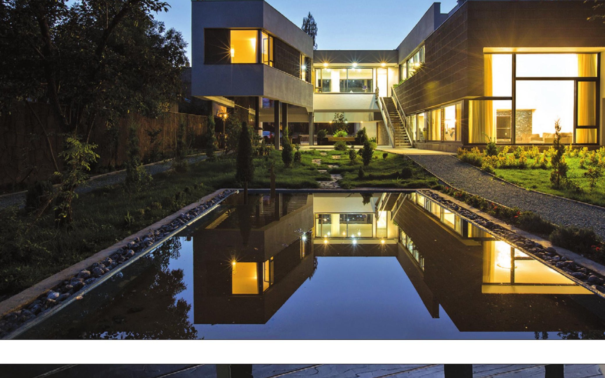 Long pool reflecting the lit villa at night