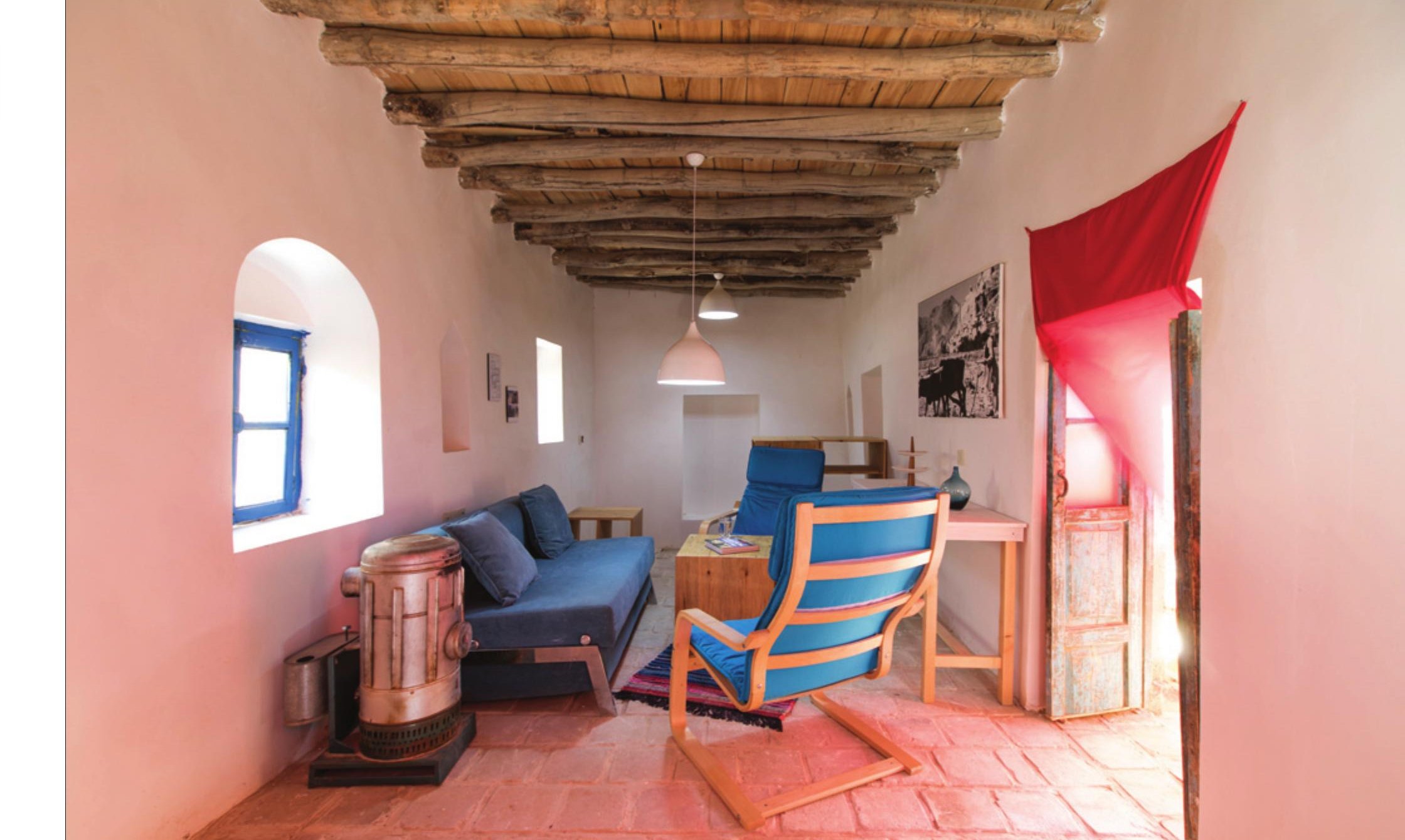 Living room with red wall and seating around a small stove