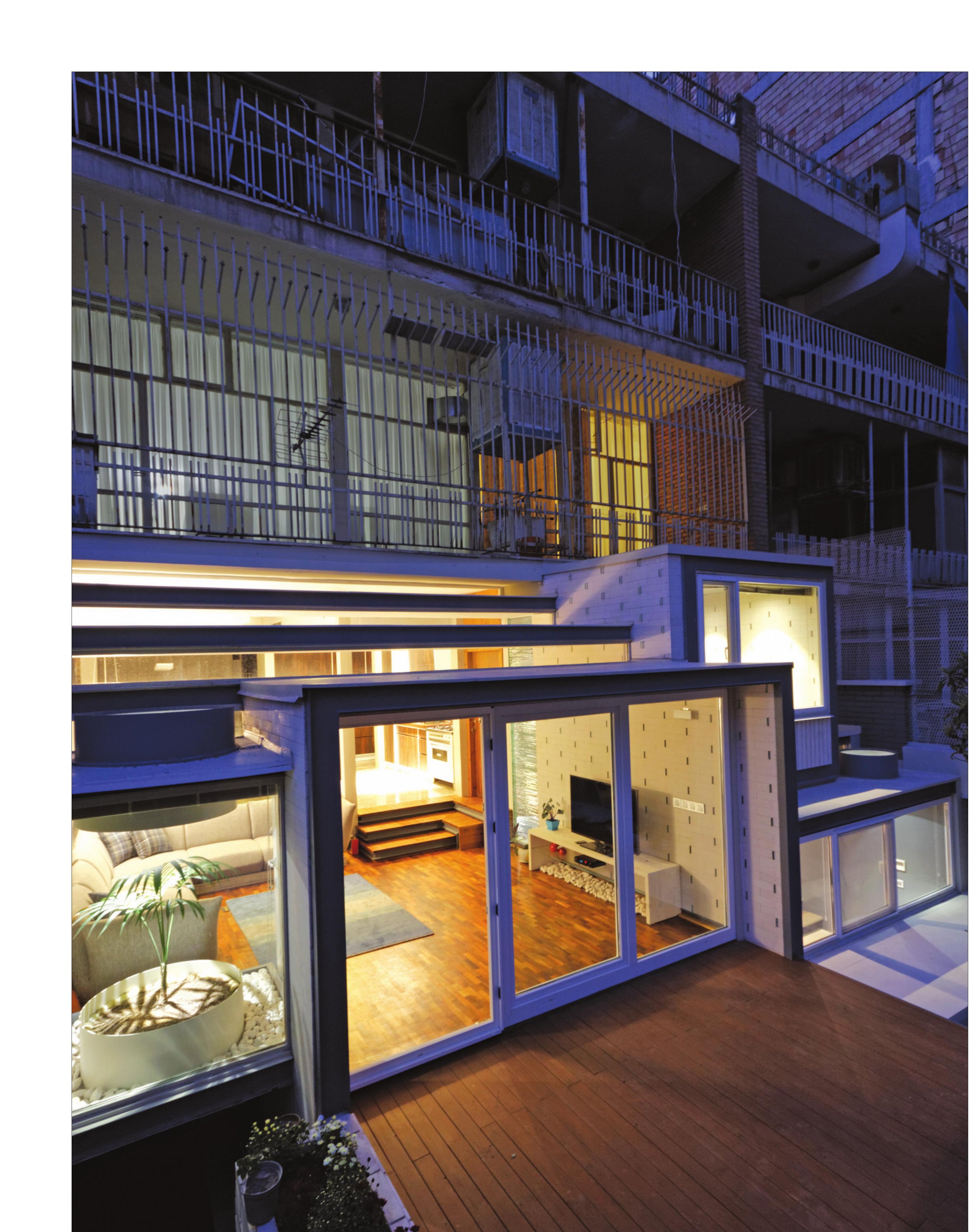 Night view of the cantilevered glass living-room extension of the House of Deflection extending into the courtyard