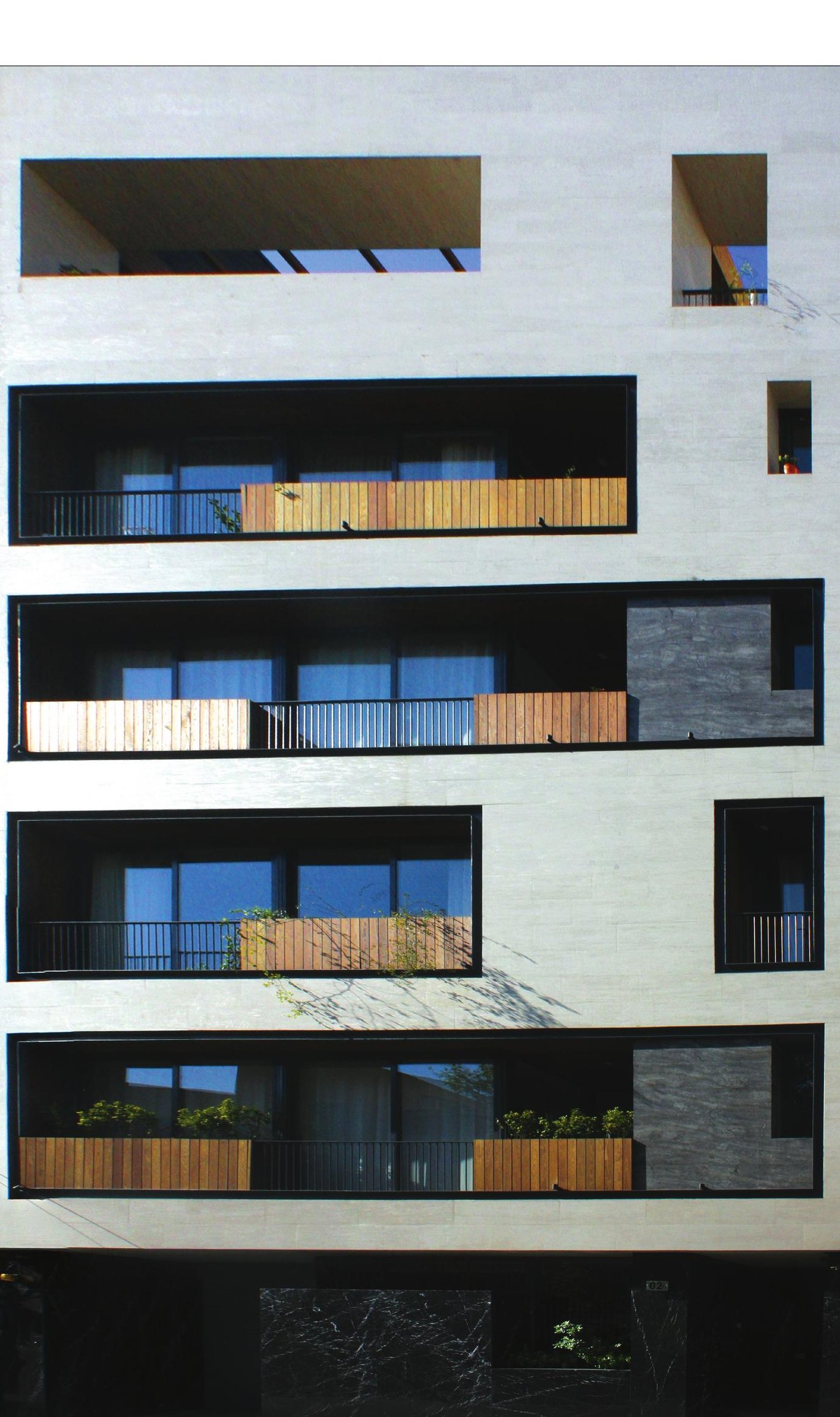 Manzarieh Residential Building — travertine facade with deeply recessed black-framed windows and wood-clad balcony fronts