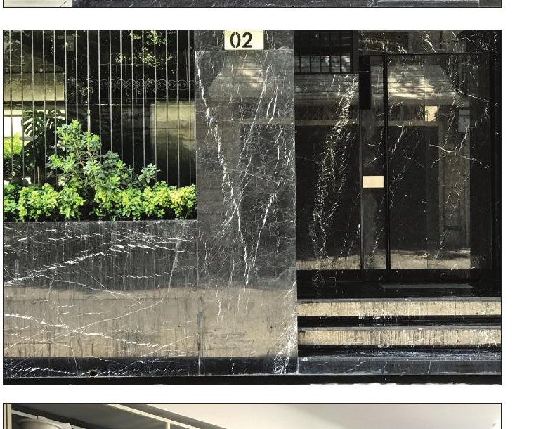 Manzarieh entrance — a dark polished stone facade with the apartment number and a wood-framed door