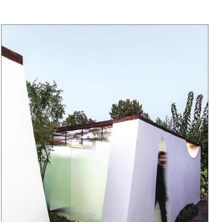 White plastered walls of At the End of Mohammad Restaurant against the garden plants and cacti