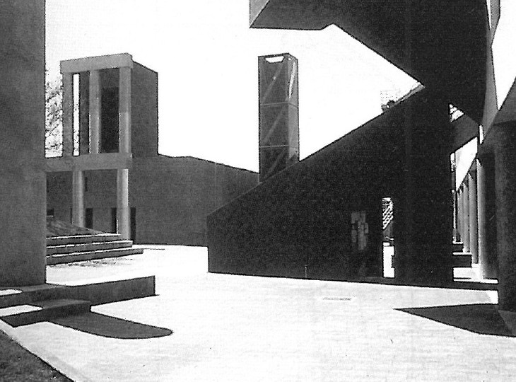 Photograph of a brick masonry building with cubic massing and small window openings