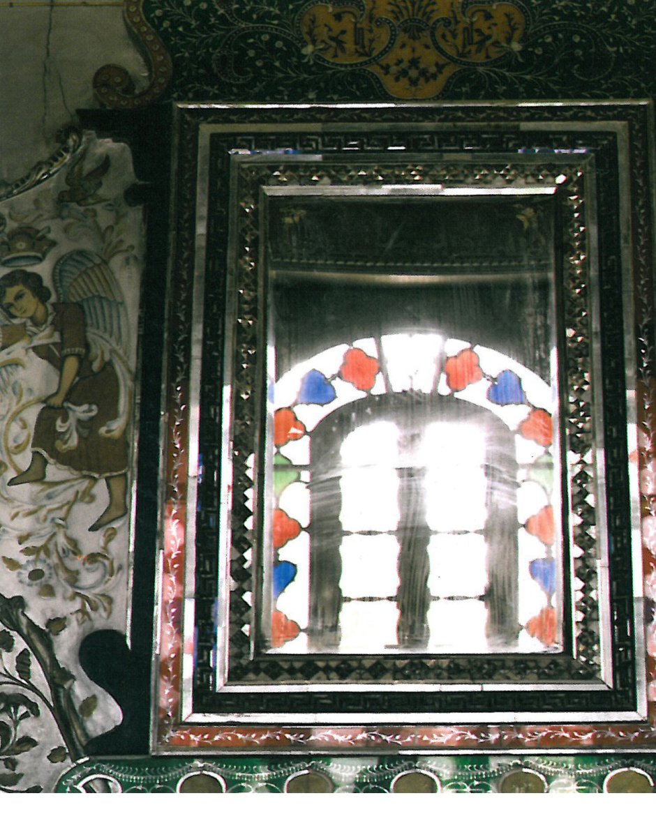 The mirror-work is lit through the stained-glass windows of the interior space.