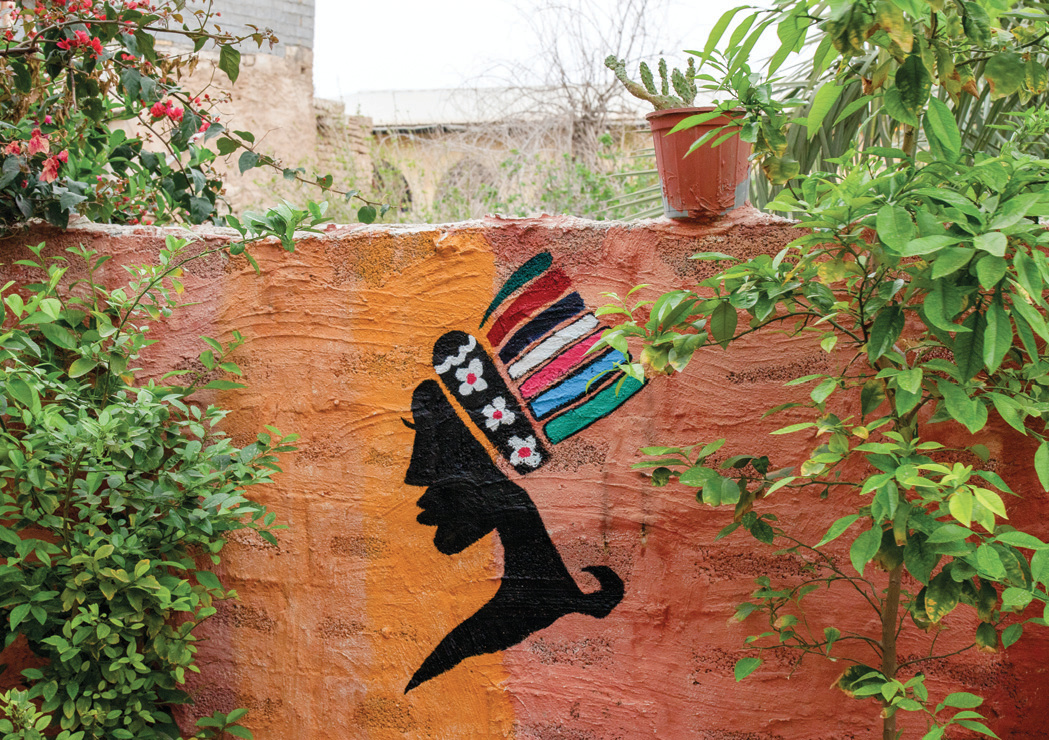 Mural of an Afro-Iranian woman with a colorful headdress on a garden wall