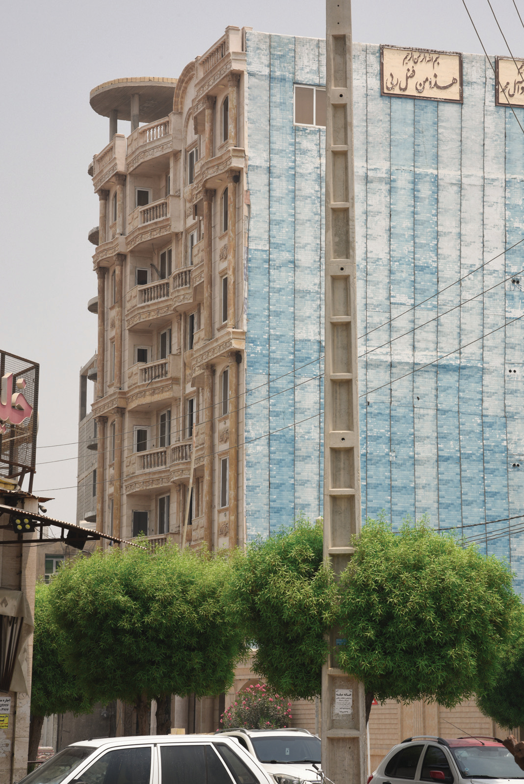 Multi-story buildings in Asaluyeh — ornate stone facades alongside blue composite cladding