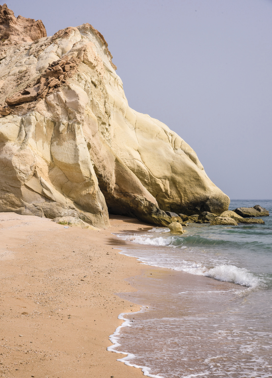Cream-colored rock formations meeting the turquoise waters at Benoud coast