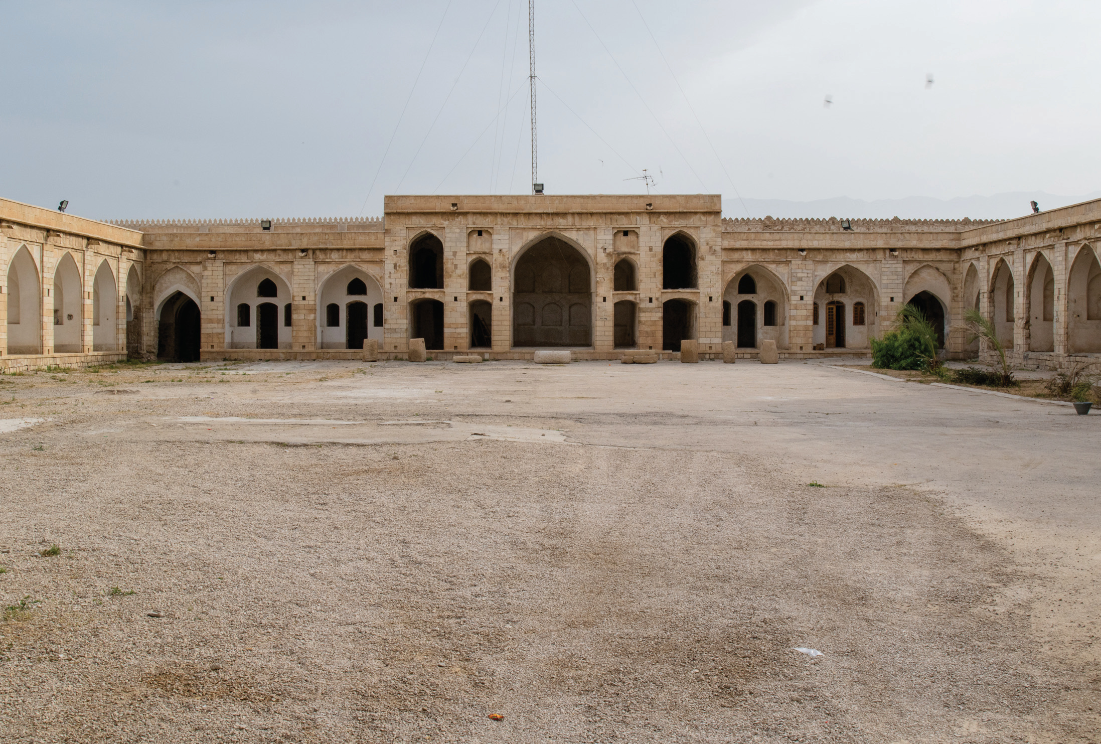 Interior courtyard of the Borazjan Caravanserai showing iwans, arcaded chambers, and stone facade