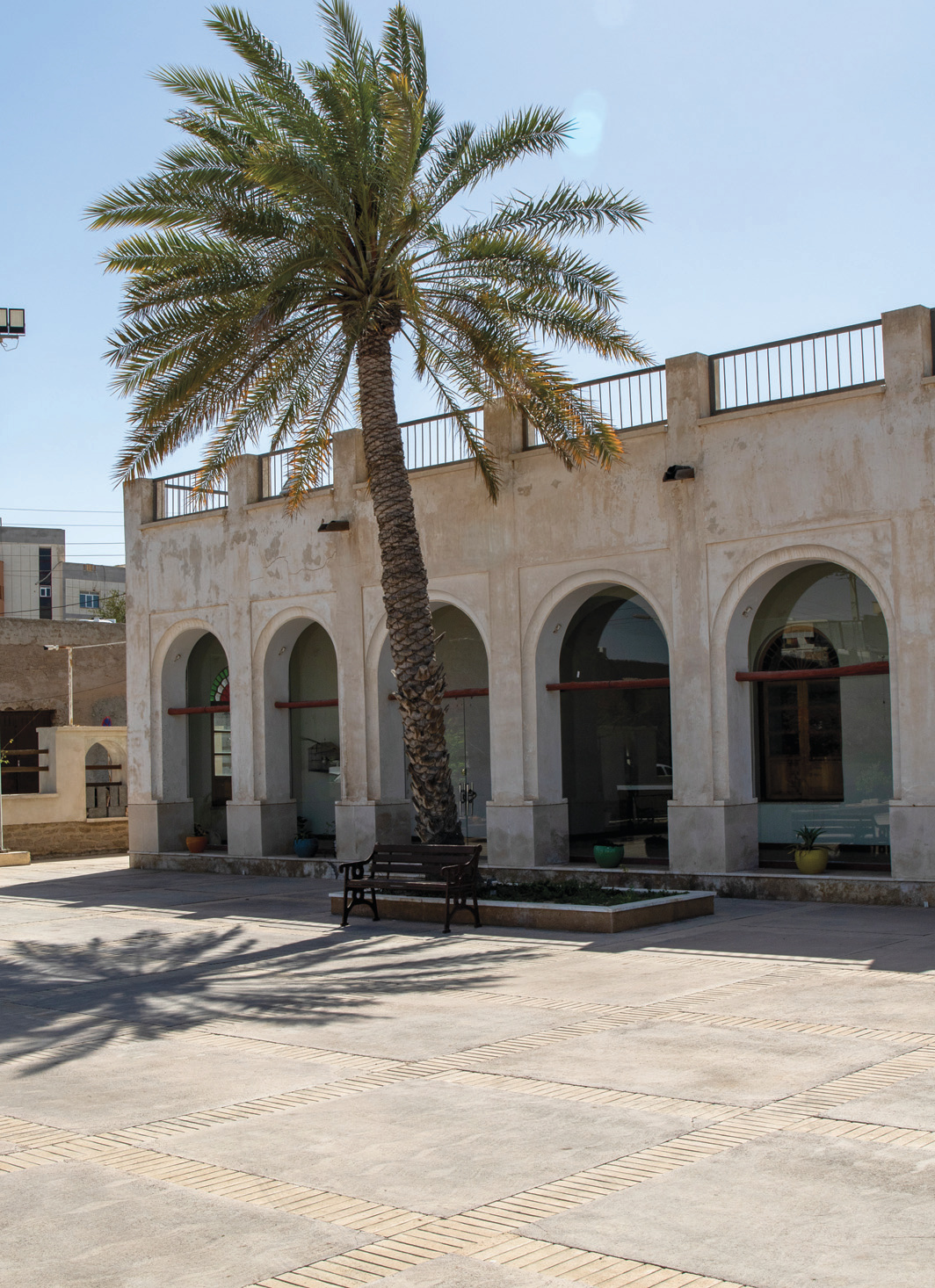 The school courtyard with a palm tree and an arched gallery beyond