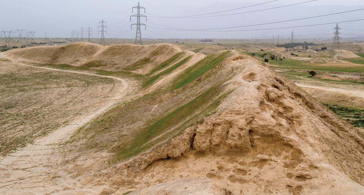 Aerial view of unexplored ancient mounds in the Dashtestan plain with power transmission lines in the background
