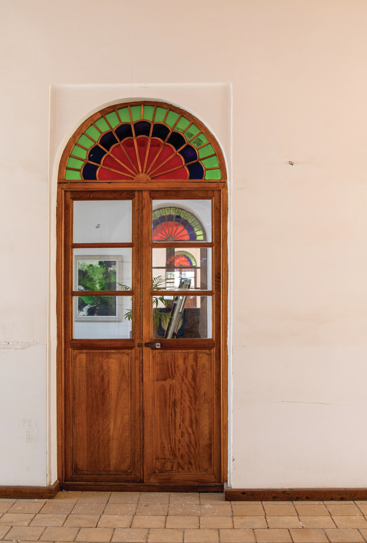 A wooden door with a colorful green and red stained glass fan lunette