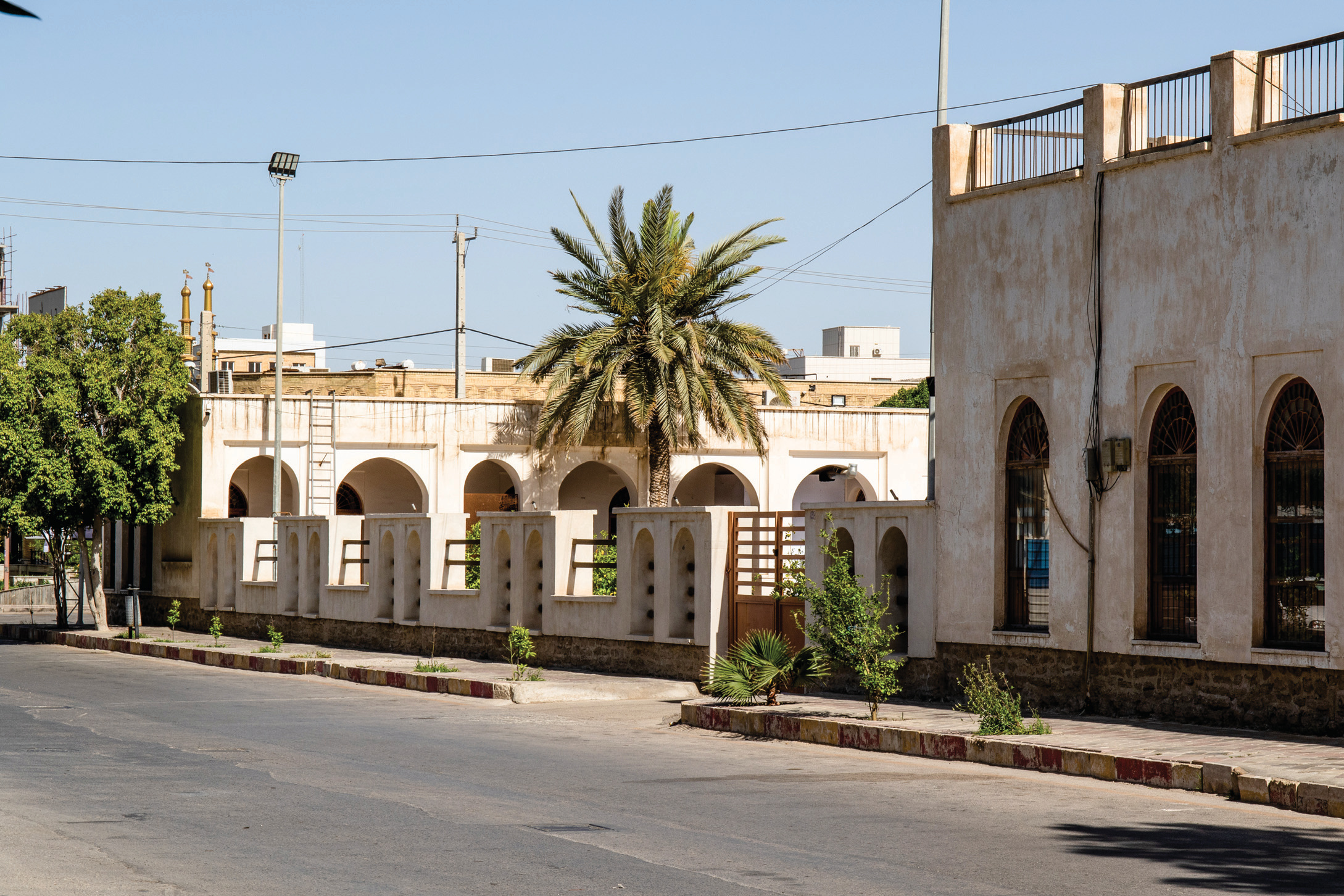 Exterior view of the Saadat School from the street, with arched facade and a palm tree