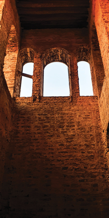High arched windows with warm light falling on coral stone walls