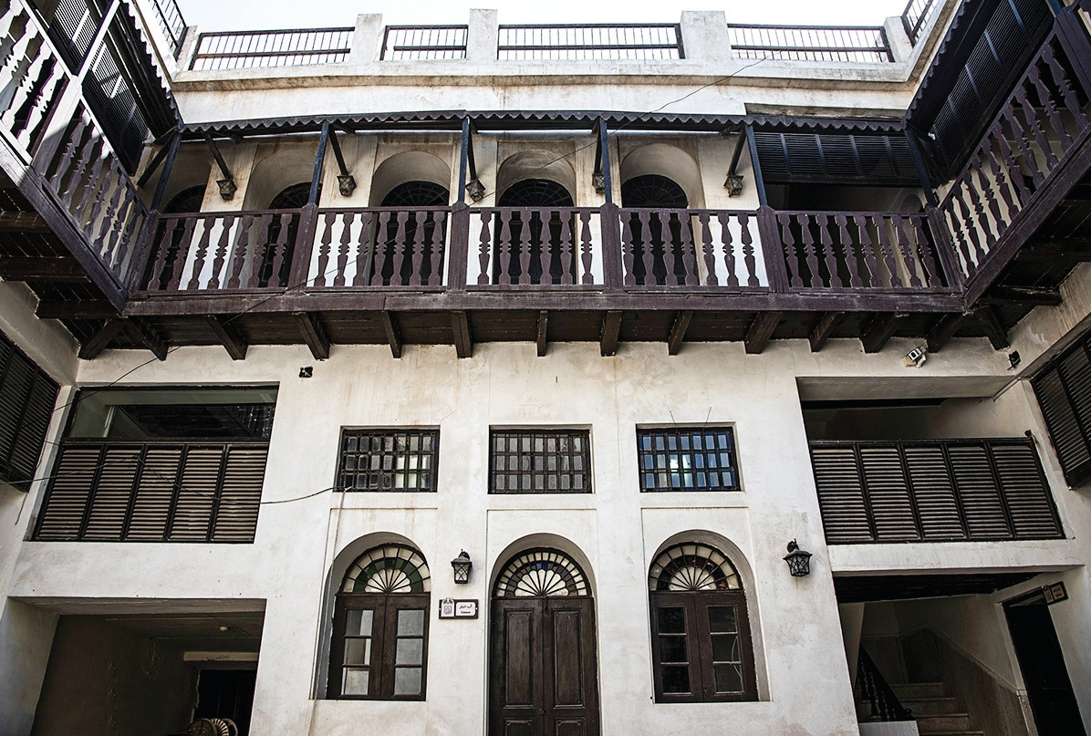 Inner courtyard looking up at two floors of arched openings and wooden balcony