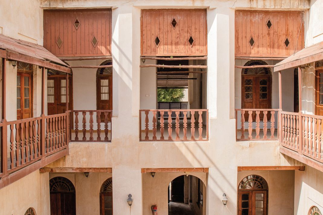 Inner courtyard of the Nouzari Edifice with two-story wooden balconies and diamond-shaped cutouts
