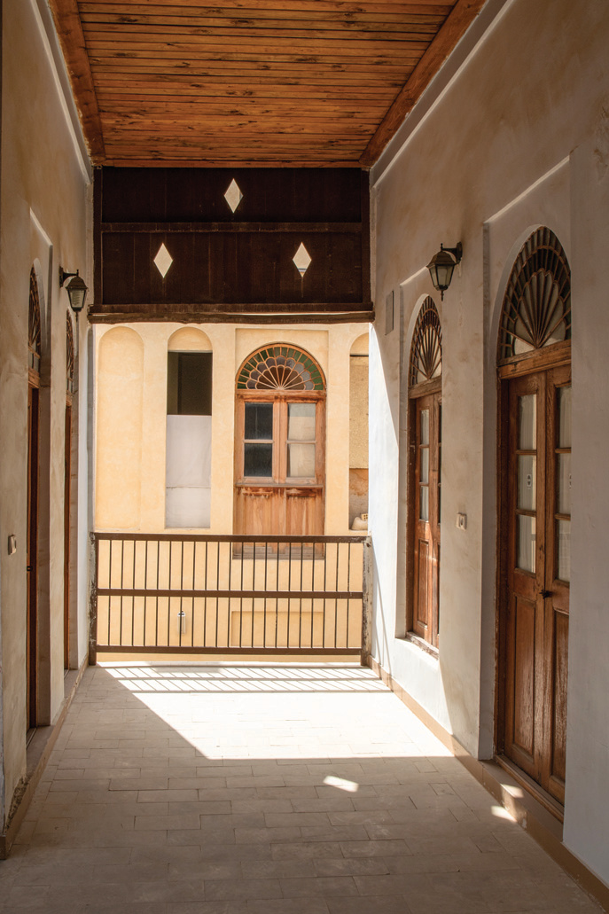 Upper floor gallery corridor of the Nouzari Edifice with arched doors, diamond cutouts, and timber ceiling