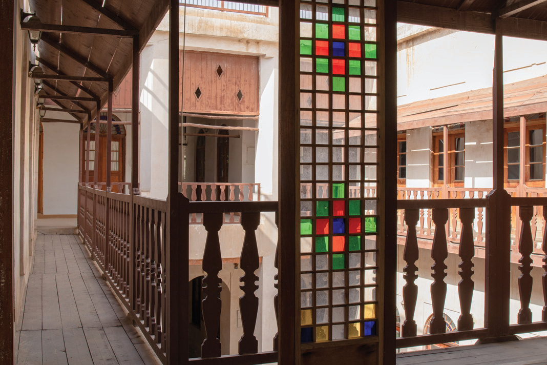 Gallery corridor with a stained glass lattice screen and wooden railings