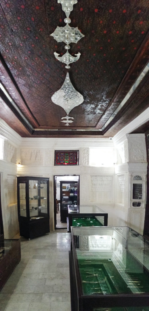 Reception room with an ornate painted ceiling in European style, glass display cases of the museum, and plasterwork walls