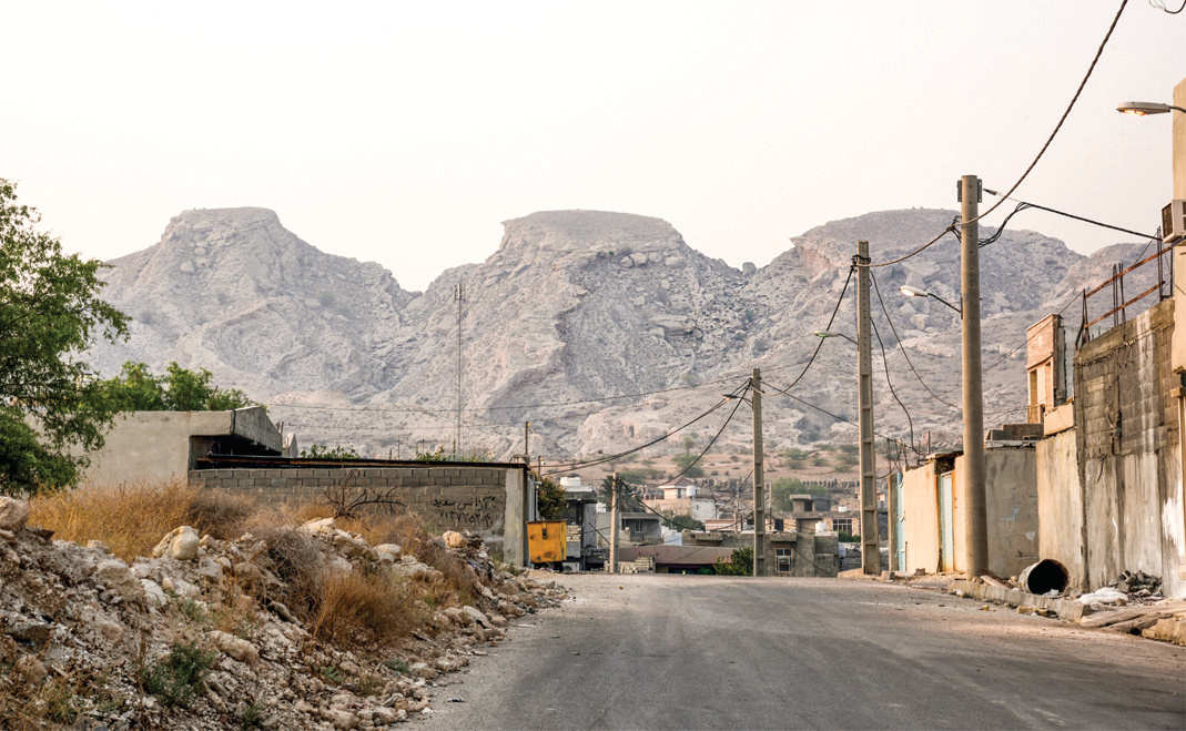 The road leading into Siraf with dramatic bare mountains rising behind the town