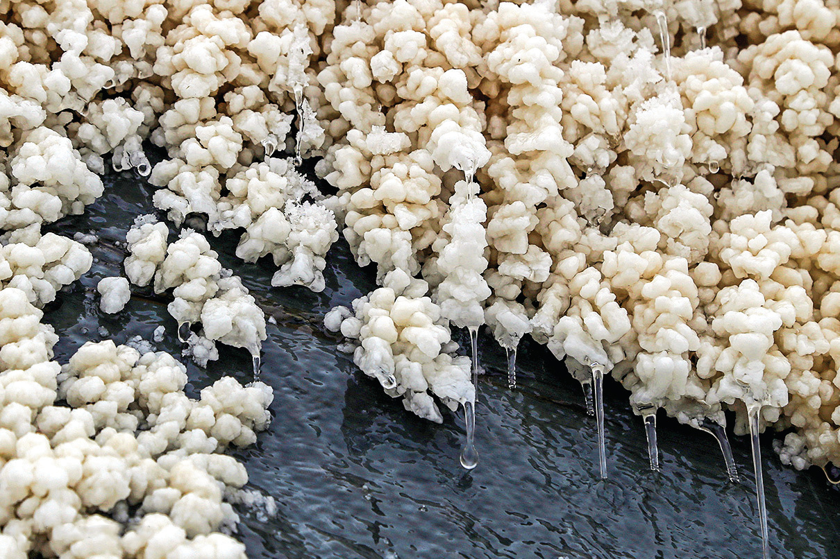Close-up of white salt crystal clusters with water dripping through them