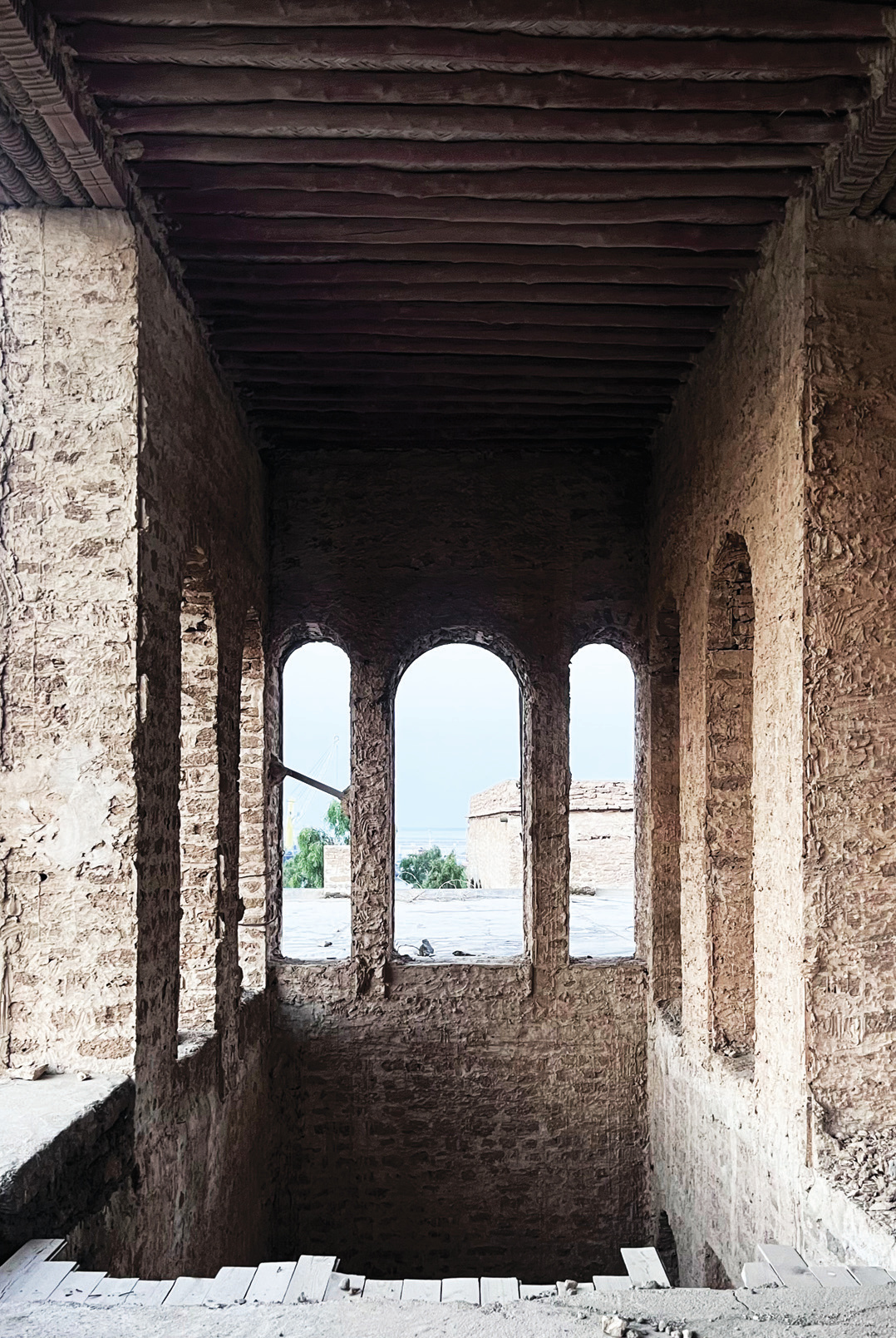 View of the sea through arched openings on an upper floor, with chandel beam ceiling