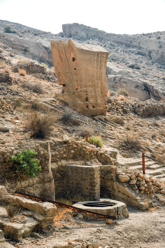 An ancient well with the large rock-cut ossuary (Gor Dakhmeh) standing behind it in the Lir Valley