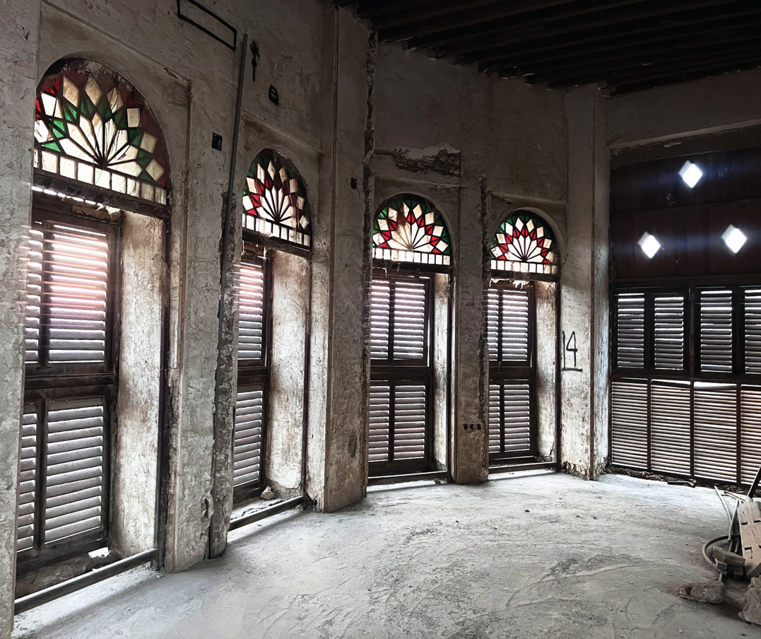 Windows with stained glass fan arches and louvered wooden shutters