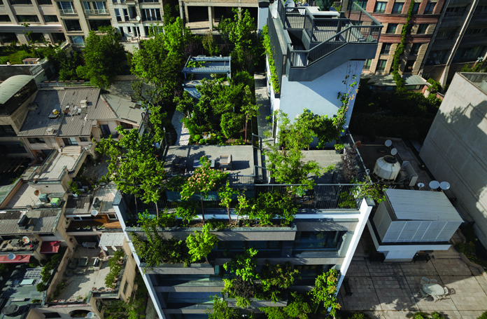 Aerial view of the Persica rooftop showing a lush canopy of trees, green coverage, and the surrounding Tehran rooftops