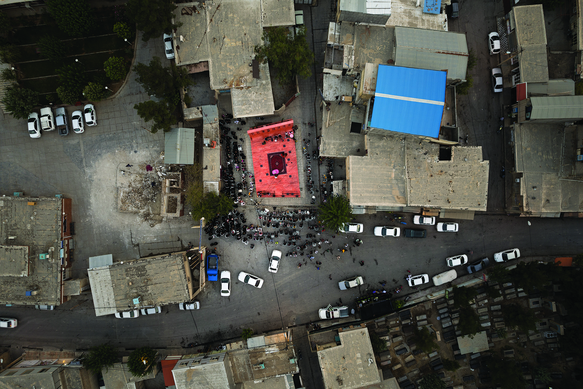 Aerial view of the red platform during a gathering, showing its relationship to the town and how it fills the opening in the urban fabric