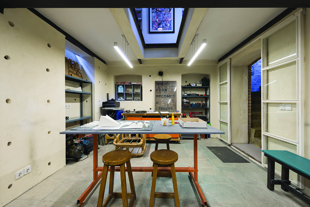 The basement workshop space with exposed brick walls, industrial lighting, and a large work table