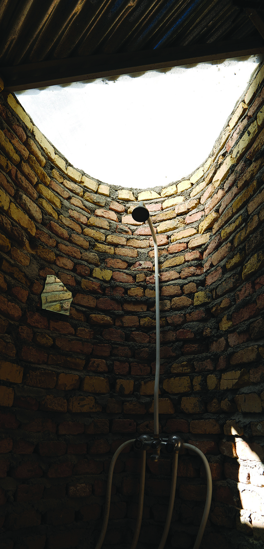 Inside the bathroom showing the semi-transparent skylight illuminating the curved brick interior
