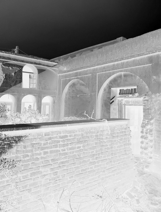 Negative photograph showing the historic courtyard with brick arches and deteriorated walls before renovation