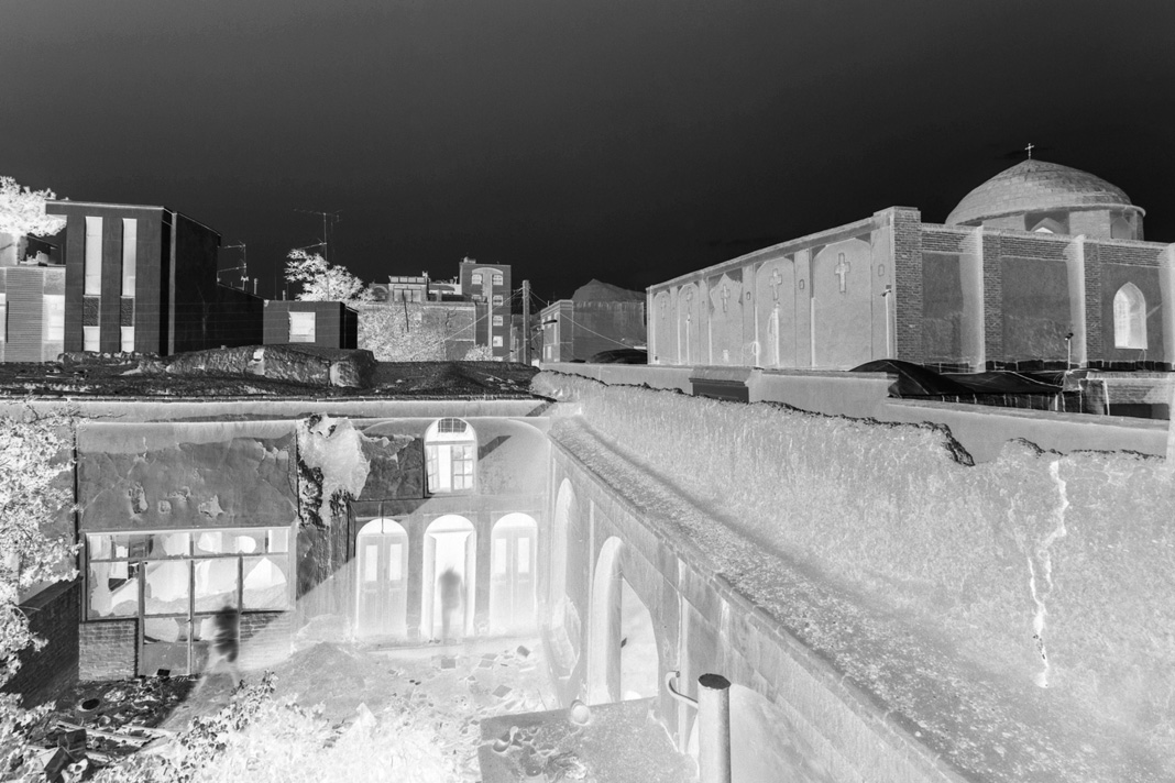 Negative photograph showing the old courtyard with deteriorating walls and the church dome visible in the background
