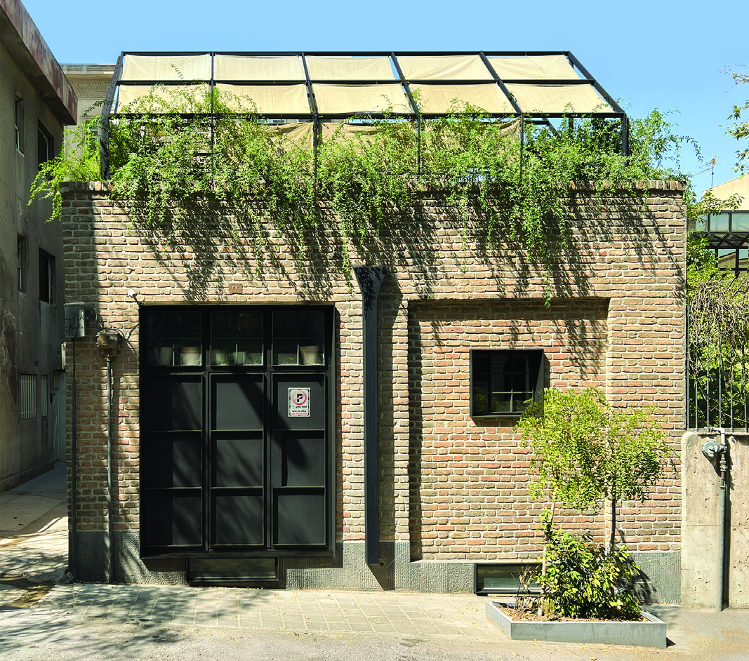 Front facade of Villa Nia showing the restored brick building with black steel-framed entrance, canopy with trailing plants