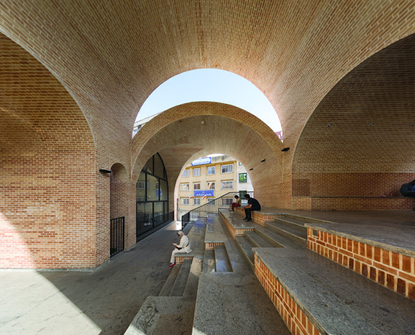 Interior view showing intersecting brick arches with stepped seating, an open skylight, and people sitting and reading