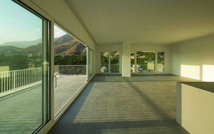 Living room with large panoramic windows framing mountain views, minimal interior with white walls
